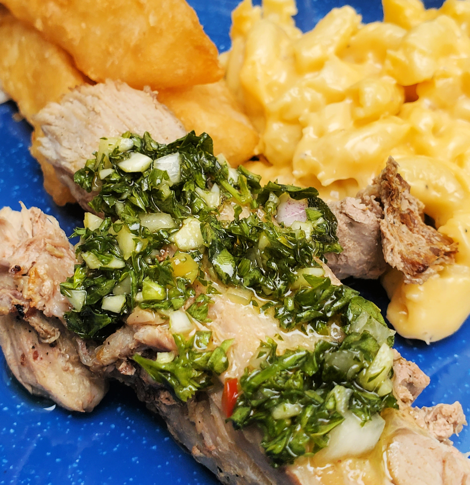 Blue plate with roasted pork and chimichurri, fried yucca, and mac & cheese